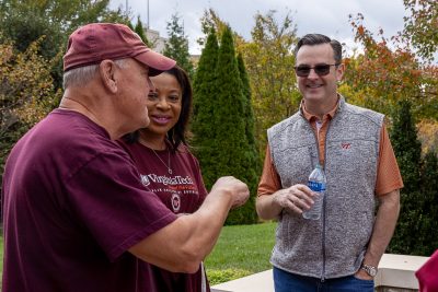 Three individuals standing outdoors and talking to each other