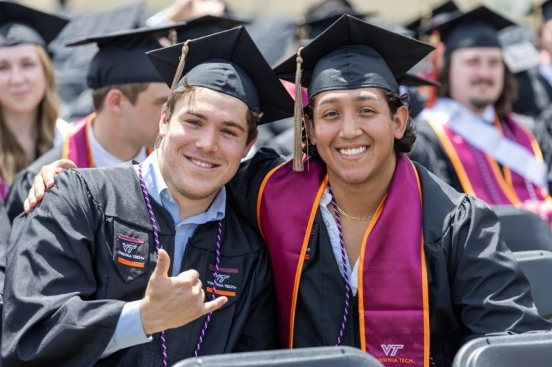 Two graduates posing for photo at Pamplin commencement.